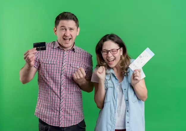 dois adultos comemorando, um rapaz com cartão na mão e a mulher com papel na mão