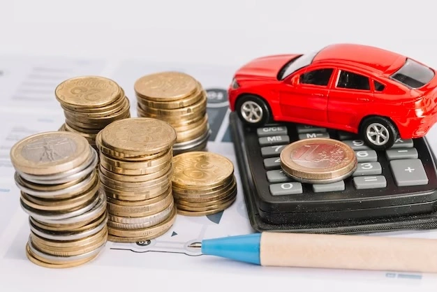 diversas moedas em cima da outra, ao lado calculadora, caneta e um carro de brinquedo